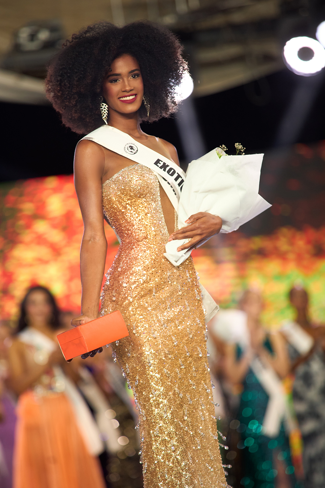 Primer plano de Smarling Mañón, modelo dominicana de DBA, sonriente y sosteniendo flores tras su triunfo en el Top Model of the World 2025 en Egipto.