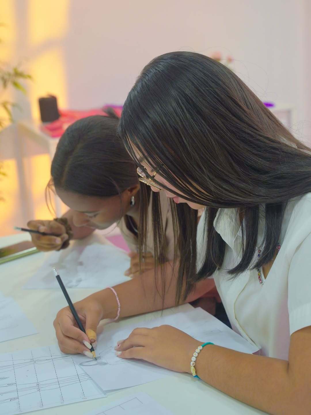 Dos jóvenes estudiantes dibujando figurines durante el curso de Ilustración de Moda en DBA.