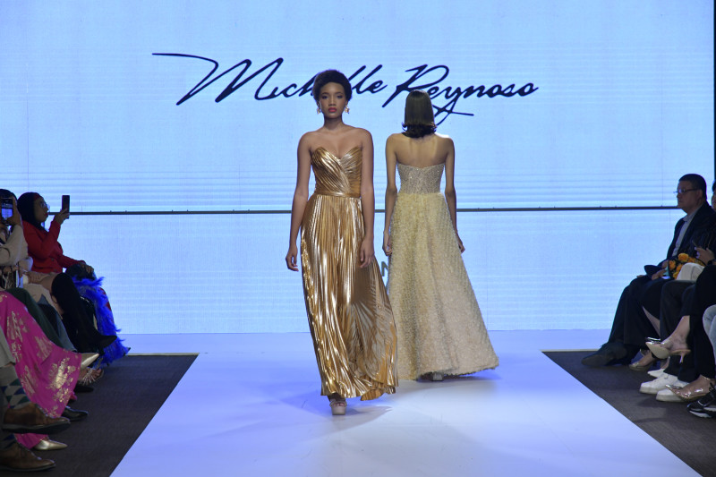Pasarela de diseñador | DBA Fashion Show – Michelle Reynoso Modelo desfila en pasarela con vestido dorado durante el DBA Fashion Show, con diseño de Michelle Reynoso.
