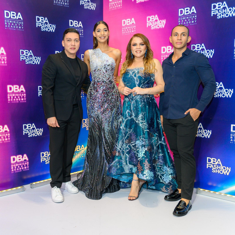 Invitados posan en el photocall del DBA Fashion Show de Dominican Beauty Academy con fondo de marca.